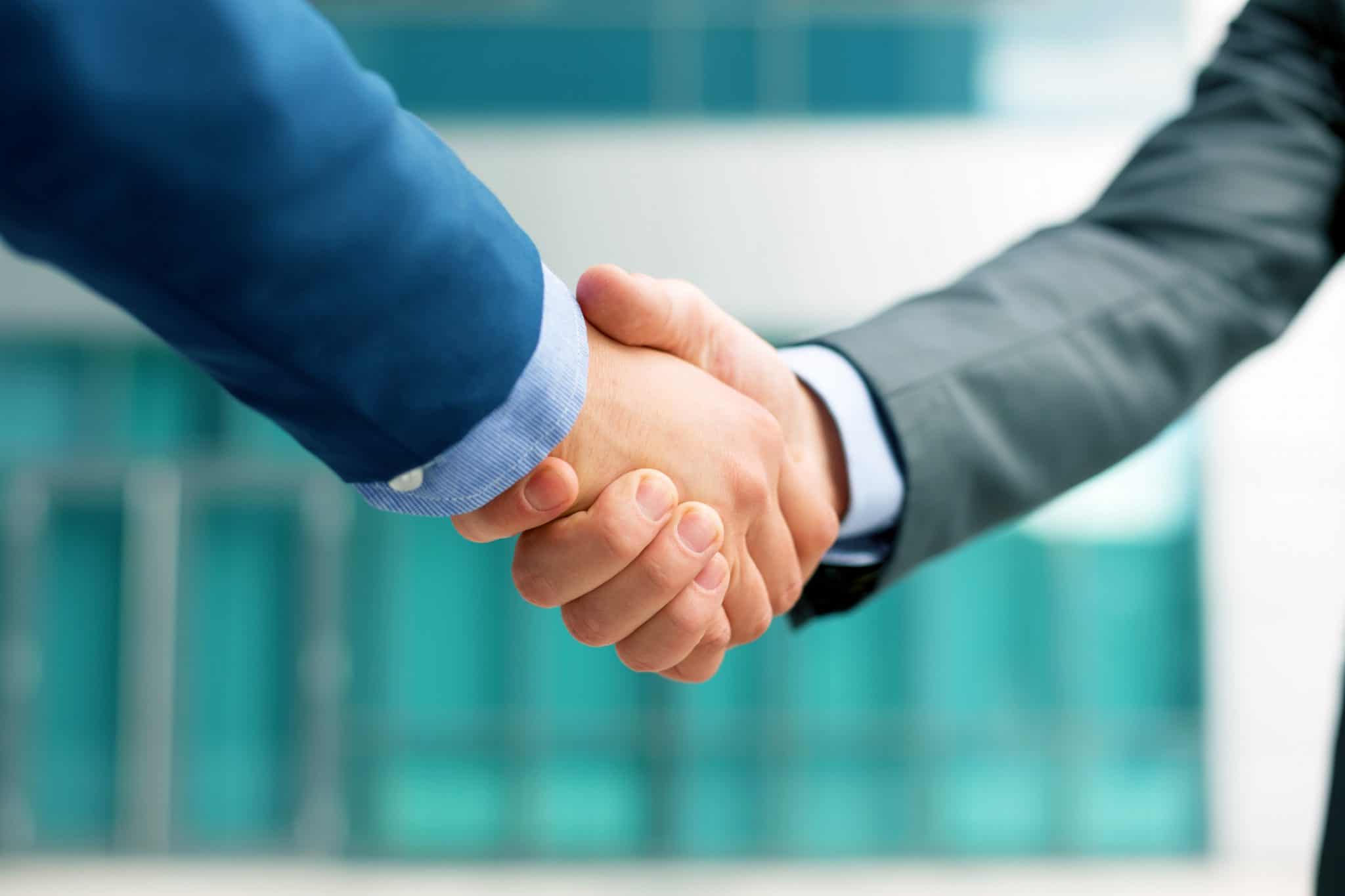 A handshake between two suited male businessmen